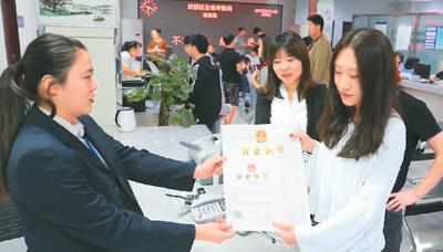 河北省承德市網(wǎng)絡(luò)代購經(jīng)營者陳晨(右)從工作人員手中接過帶有統(tǒng)一社會信用代碼的營業(yè)執(zhí)照。 劉環(huán)宇攝(人民圖片)