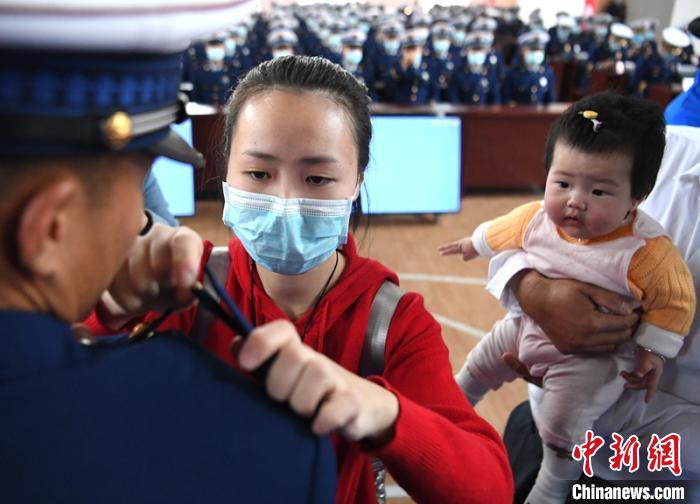 新消防員楊振的妻子彭莉與女兒現(xiàn)場見證丈夫加入“火焰藍(lán)”的神圣時刻?！⒅铱?攝