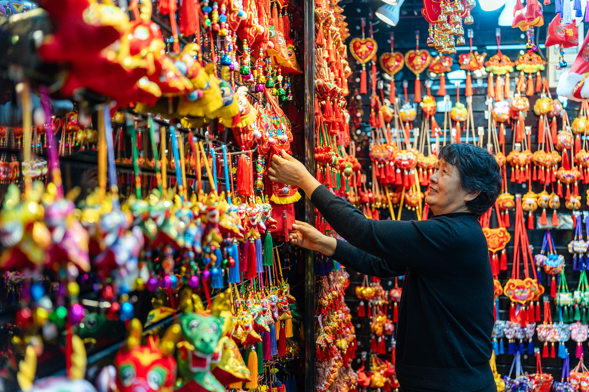 2023年12月11日，金華義烏國際商貿(mào)城，龍年喜慶用品掛滿攤位，顧客正在挑選中。